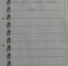 Ein handgeschriebener Brief von Schüler:innen der Klasse 2a mit dem Text „Der Ausflug war schön. Wir kommen wieder! Eure 2a“ auf linierten Papier mit kleinen Hausmotiven am Rand.