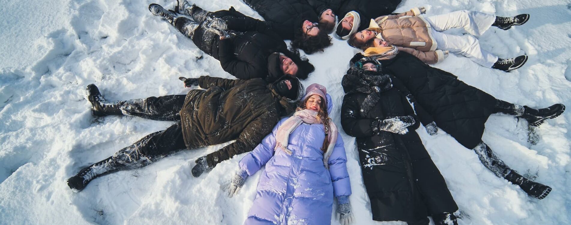 Junge Schüler machen während eines Winter-Fotoshootings Schneeengel im Schnee.