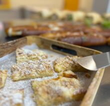 Frisch gebackener Streuselkuchen mit Puderzucker auf einem Holztablett in der Betriebskantine